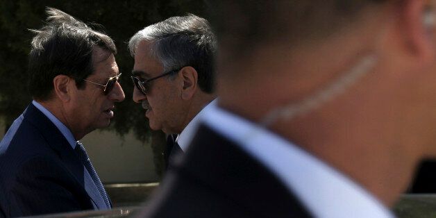 FILE - In this Wednesday, Sept. 14, 2016 file photo, Cypriot President Nicos Anastasiades, left, and breakaway Turkish Cypriot leader Mustafa Akinci, right, talk as a guard stands in front of a car after their meeting aimed at reunifying the ethnically divided island, at the disused Nicosia airport inside a United Nations controlled buffer zone in this divided island of Cyprus. A United Nations spokesman says on Wednesday, Oct. 27, 2016, the leaders of ethnically divided Cyprus' Greek and Turkish speaking communities will conduct a key phase of reunification talks in Mont Pelerin, Switzerland next month Nov. 7-11. Aleem Siddique said the talks between Anastasiades and Akinci will focus on how much territory each side will administer under an envisioned federation. (AP Photo/Petros Karadjias, File)