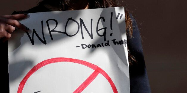 Senya Merchant holds a sign against President-elect Donald Trump's now-defunct Trump University Friday, Nov. 18, 2016, in San Diego. Trump agreed Friday to pay $25 million to settle several lawsuits alleging that his former school for real estate investors defrauded students who paid up to $35,000 to enroll in Trump University programs.(AP Photo/Gregory Bull)