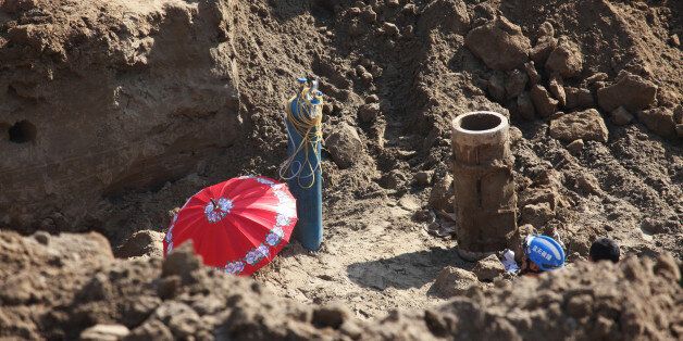 BAODING, CHINA - NOVEMBER 08: A red umbrella shades the dry well in which the boy trapped at Zhongmengchang Village on November 8, 2016 in Baoding, Hebei Province of China. Over 50 excavators, some one thousand rescuers and residents have worked for over 60 hours to rescue the 5-year-old boy who fell into a 40-meter deep dry well sine the noon on November 6 in Lixian County, Hebei. (Photo by VCG/VCG via Getty Images)
