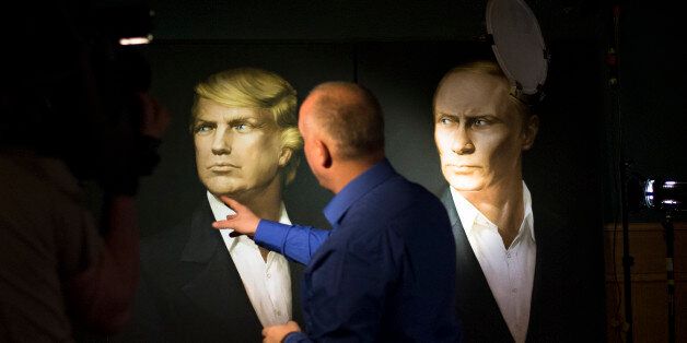 FILE - In this Wednesday, Nov. 9, 2016, file photo, a journalist points at a portrait of U.S. President-elect Donald Trump, with a portrait of Russian President Vladimir Putin during a live telecast of the U.S. presidential election in the Union Jack pub in Moscow, Russia. Putin's spokesman Peskov said Thursday that one way Trump could help build confidence with Russia after he becomes president would be to persuade NATO to slow down its expansion or withdraw its forces from Russia's borders. (A