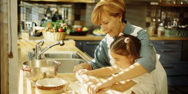 Grandmother helping granddaughter roll out pastry