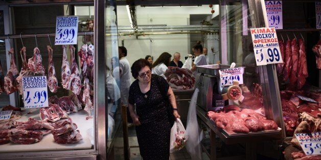 An elderly woman shops meat at Varvakios market in Athens, Saturday, July 25, 2015. Greece on Friday invited the International Monetary Fund to participate in its negotiations with European creditors over a vital third bailout. The talks are expected to start next week after a few days' delay and must conclude before Greece faces another big repayment Aug. 20. (AP Photo/Giannis Papanikos)