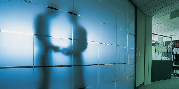 Silhouette of a Businessman Standing Behind a Frosted Glass Window in An Open Plan office Receiving a Bribe From Another Businessman