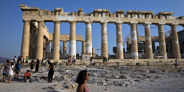 Tourists stand in front of the Parthenon temple as they visit the archaeological site of the Acropolis hill in Athens, Greece July 26, 2015. Talks between Greece and its international creditors over a new bailout package will be delayed by a couple of days because of organizational issues, a finance ministry official said on Saturday. REUTERS/Ronen Zvulun