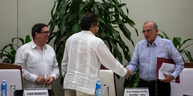 Humberto de La Calle, right, head of Colombia's government peace negotiation team, right, shakes hands with Ivan Marquez, chief negotiator of the Revolutionary Armed Forces of Colombia, or FARC, as Cuba's Foreign Minister Bruno Rodriguez, watches, after the signing of the latest peace accord between the two sides in Havana, Cuba, Saturday, Nov. 12, 2016. Colombia's government and its largest rebel group signed a new, modified peace accord on Saturday following the surprise rejection of an earlier deal by voters in a referendum. (AP Photo/Desmond Boylan)