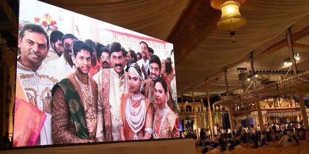 Indian mining tycoon, Gali Janardhan Reddy, (C) is seen on a big screen as he poses with his daughter Bramhani (2R) and son-in-law, Rajeev Reddy (2L) during their wedding at the Bangalore Palace Grounds in Bangalore.A controversial Indian mining tycoon has taken over a royal palace and flown in Brazilian dancers at a reported cost of 75 million dollars to celebrate his daughter's wedding, as the country reels from a cash crisis. / AFP / STRINGER (Photo credit should read STRINGER/AFP/Gett