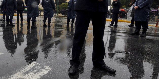 Policemen stand guard in front of a crowd of Greeks watching a military parade during Independence Day celebrations in Athens, March 25, 2015. Thousands of Greeks braved heavy rainfall on Wednesday to watch the Independence Day parade in front of the parliament after being banned in previous years for security reasons. REUTERS/Yannis Behrakis
