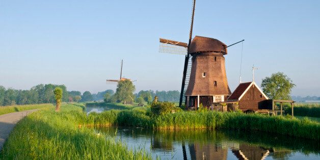 Two windmills along a canal and a country road in warm morning light near Rustenburg, Netherlands