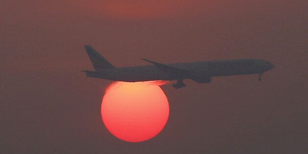 A plane flies over the setting sun in the sky at Beijing International Airport, China, March 2, 2016. REUTERS/Kim Kyung-Hoon/File Photo