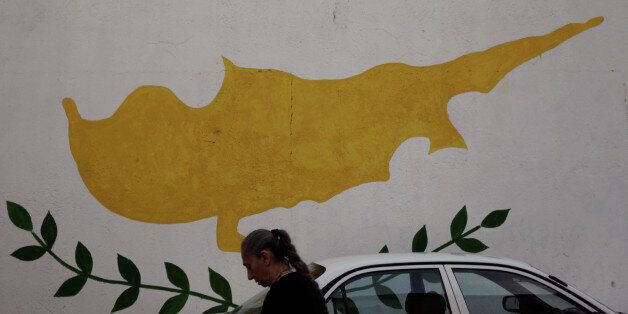 A woman walks in front of Cypriot flag painted on a wall in capital Nicosia, Cyprus November 11, 2016. REUTERS/Yiannis Kourtoglou