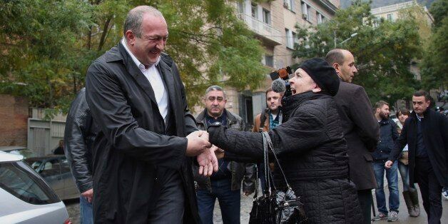 Georgian President Giorgi Margvelashvili, left, is greeted by a Georgian woman outside a polling station during a parliamentary election runoff in Tbilisi, Georgia, Sunday, Oct. 30, 2016. The governing party in the former Soviet republic of Georgia aims to win a constitutional majority of parliament seats in the second round of national voting Sunday. (Leli Blagonravova/Presidential Press Service Handout Photo via AP)