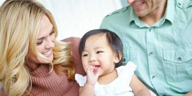 A happy couple spending time with their beautiful adopted daughter while at home