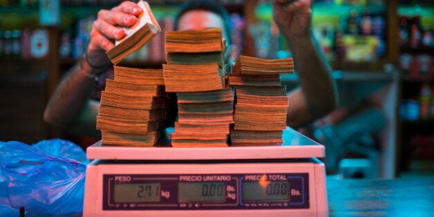 A manager weighs banknotes on a scale at a bakery in Caracas, Venezuela, on Thursday, Oct. 13, 2016. Once one of the world's strongest currencies, the bolivar has been reduced to a nuisance. Basic purchases require hundreds of bills. The currency is so devalued and each purchase requires so many bills that instead of counting, businesses are weighing them. Photographer: Manaure Quintero/Bloomberg via Getty Images