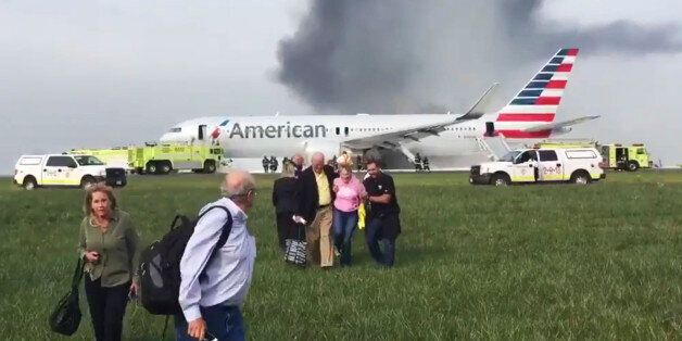 In this photo provided by passenger Jose Castillo, fellow passengers walk away from a burning American Airlines jet that aborted takeoff and caught fire on the runway at Chicago's O'Hare International Airport on Friday, Oct. 28, 2016. Pilots on Flight 383 bound for Miami reported an engine-related mechanical issue, according to an airline spokeswoman. (Jose Castillo via AP)