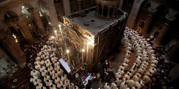 TOPSHOT - Roman Catholic clergymen hold candles as they circle the Aedicula during the Holy Thursday (Maundy Thursday) mass at the Church of the Holy Sepulchre in Jerusalem's Old City on March 24, 2016. / AFP / GALI TIBBON (Photo credit should read GALI TIBBON/AFP/Getty Images)