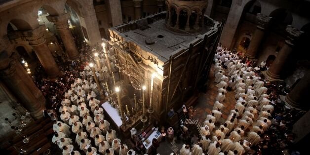 TOPSHOT - Roman Catholic clergymen hold candles as they circle the Aedicula during the Holy Thursday (Maundy Thursday) mass at the Church of the Holy Sepulchre in Jerusalem's Old City on March 24, 2016. / AFP / GALI TIBBON (Photo credit should read GALI TIBBON/AFP/Getty Images)