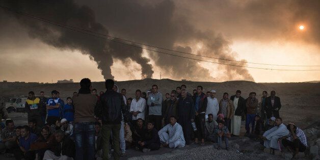 Men are held by Iraqi national security agents, to be interrogated at a checkpoint, as oil fields burn in Qayara, south of Mosul, Iraq, Saturday, Nov. 5, 2016. Islamic State fighters launch counterattacks in the thin strip of territory Iraqi special forces have recaptured in eastern Mosul, highlighting the challenges ahead as the battle moves into more densely populated neighborhoods where coalition air power must be used more selectively. (AP Photo/Felipe Dana)