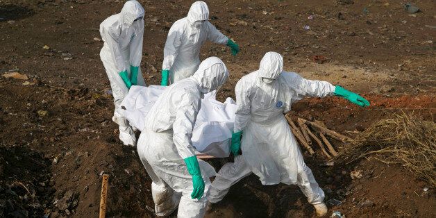 Health workers carry the body of a suspected Ebola victim for burial at a cemetery in Freetown December 21, 2014. REUTERS/Baz Ratner/File Photo