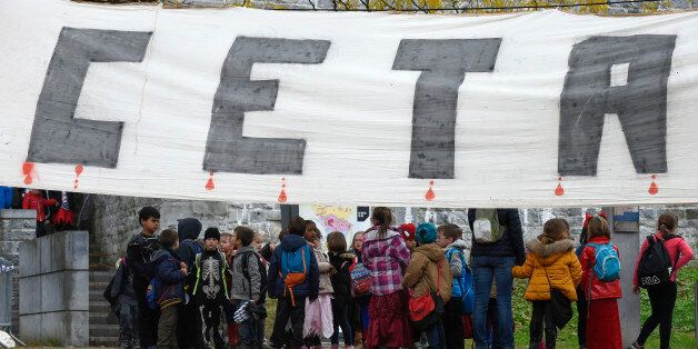 Children walk past a baner hung close to the Walloon parliament in Namur on October 28, 2016. Parliament in Belgium's Wallonia region approved on October 28, a landmark EU-Canada free trade agreement after marathon talks produced a compromise clearing the way for the European Union to sign the pact. By 58 votes to five, parliament in Namur south of Brussels became the first of the country's three French-speaking communities to back the accord, allowing the Belgian government to give the EU its blessing to go ahead with the deal. / AFP / JOHN THYS (Photo credit should read JOHN THYS/AFP/Getty Images)