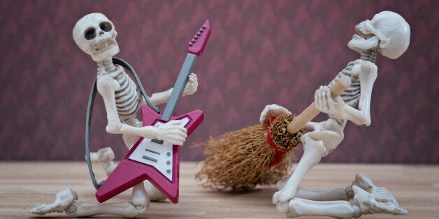 Skeleton poses with broom as playing guitar