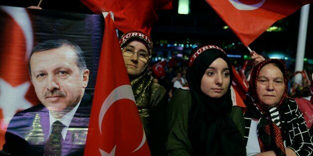 A woman holds a photograph of Turkish President Recep Tayyip Erdogan as others wave flags of their country during an anti coup rally at Taksim square in Istanbul, Wednesday, Aug. 10, 2016. The failed coup left more than 270 people dead and about 18,000 people have been detained or arrested. (AP Photo/Thanassis Stavrakis)