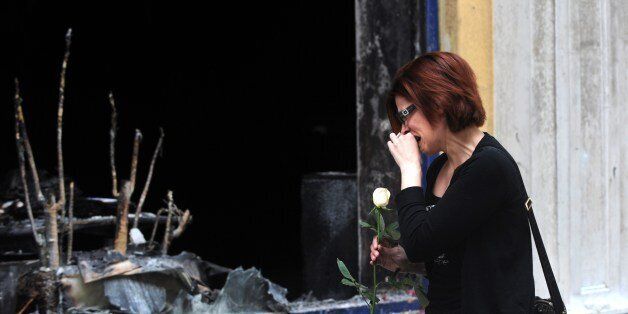 A woman cries as she puts flowers on May 6, 2010 in front a branch of the Marfin bank where three people were killed in Athens. A fire-bomb attack on a bank in Greece killed at least three people on May 5, as police fought pitched battles with striking protestors furious at brutal budget cuts designed to avert national bankruptcy. Greek unions mobilised Thursday for new demonstrations against draconian austerity cuts as the government raced to push the unprecedented measures through parliament a day after deadly rioting. AFP PHOTO / DIMITAR DILKOFF (Photo credit should read DIMITAR DILKOFF/AFP/Getty Images)