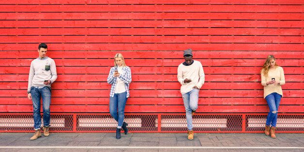 Group of multiracial fashion friends using smartphone with red wood background - Technology addiction in urban lifestyle with disinterest towards each other - Addicted people to modern mobile phones