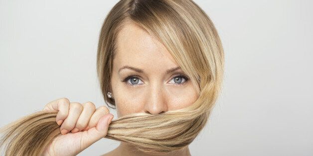 Portrait of blonde woman holding hair over face