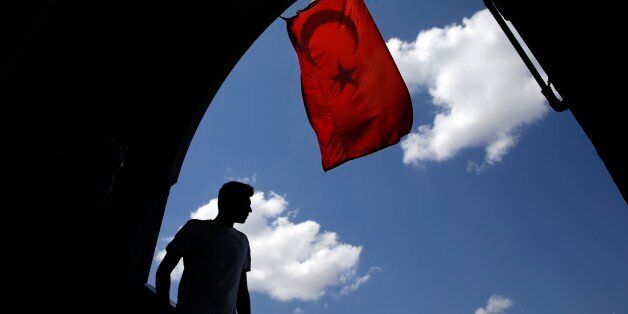 A pedestrian passes under a Turkish flag in Istanbul, Sunday, Aug. 14, 2016. Turkish authorities have prepared an official request for the temporary arrest of United States-based Islamic cleric Fethullah Gulen over his alleged involvement in the coup attempt on July 15, Turkey's state-run Anadolu news agency said Saturday. (AP Photo/Thanassis Stavrakis)