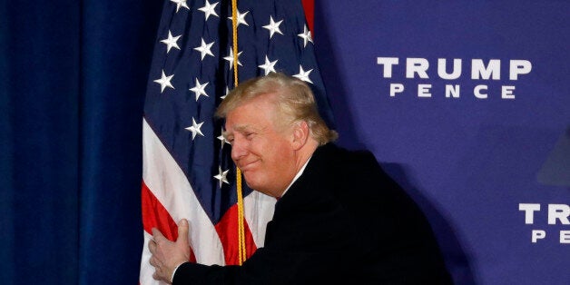 Republican presidential candidate Donald Trump hugs the American flag after speaking at a rally Monday, Nov. 7, 2016 in Leesburg, Va. (AP Photo/Alex Brandon)