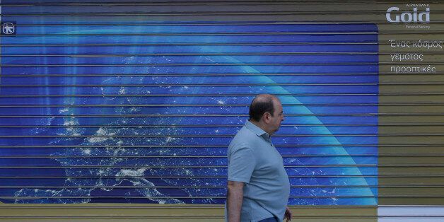 A man passes a closed bank with a shutter dipicting the European map, in Athens, Monday, June 29, 2015. Greece's five-year financial crisis took its most dramatic turn yet, with the cabinet deciding that Greek banks would remain shut for six business days and restrictions would be imposed on cash withdrawals. (AP Photo/Thanassis Stavrakis)