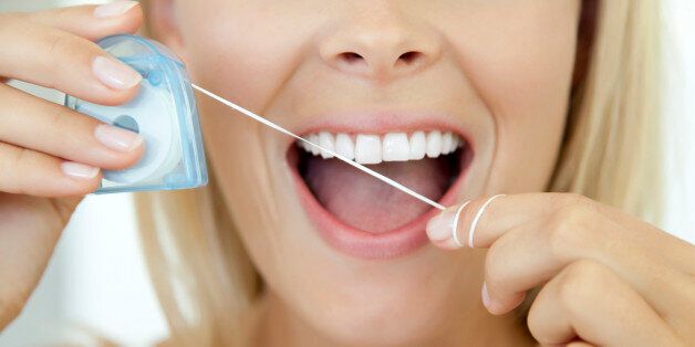 Woman using dental floss, cropped