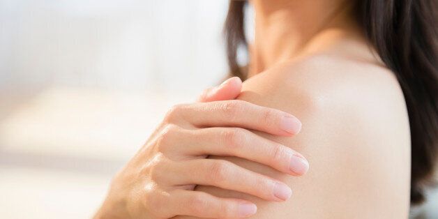 Mixed race woman rubbing lotion into skin