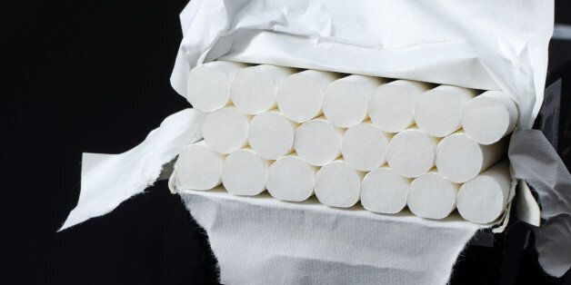 Lot of white cigarets in paper box isolated on black background.