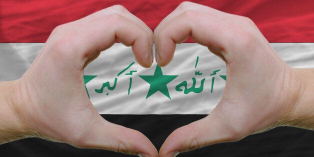 Gesture made by hands showing symbol of heart and love over iraq flag