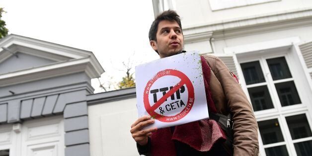 A demonstrator holds a poster reading 'Stop TTIP - Stop CETA' ahead of an emergency meeting of all Belgium federal entities on the EU-Canada Comprehensive Economic and Trade Agreement (CETA) in Brussels on October 24, 2016. The small Belgian region refused on October 24 to bow to growing pressure to back the key trade deal with Canada, heightening tensions within Belgium and Europe as well as with historic allies in North America. Riding a rising wave of Western populist distrust of international trade deals, French-speaking Wallonia's parliament stuck to its refusal to heed a late Monday EU deadline to support the pact. / AFP / EMMANUEL DUNAND (Photo credit should read EMMANUEL DUNAND/AFP/Getty Images)