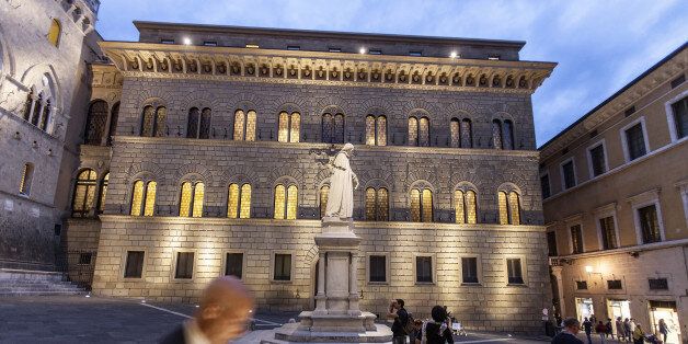 A pedestrian checks his smartphone device in Piazza Salimbeni, as the statue of Sallustio Bandini, an economist and politician, stands in front of Monte dei Paschi di Siena SpA bank headquarters in Siena, Italy, on Tuesday, Sept. 20, 2016. Monte Paschi's stock has dropped about 82 percent this year and the bank is struggling to avoid a state bailout that could wipe out thousands of retail bondholders. Photographer: Alberto Bernasconi/Bloomberg via Getty Images