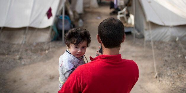 A Syrian man holds his eight month old daughter at Ritsona refugee camp north of Athens, on Wednesday, Oct. 19, 2016. About 600 people, mostly families with small children, live in tents in the camp, which officials say will soon be replaced by prefabricated homes. (AP Photo/Petros Giannakouris)
