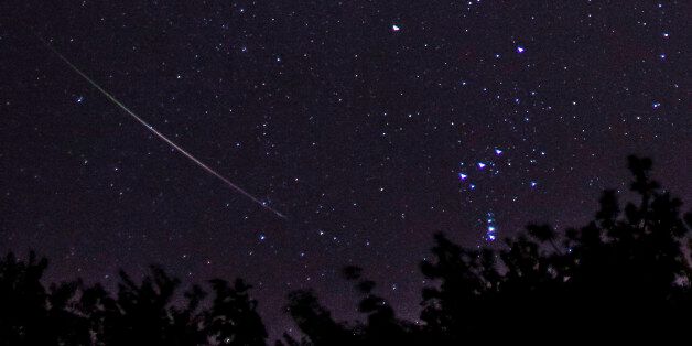 A Meteor streaking away from the constellation Orion, at right. Orion's belt visible. Taken during Orionids meteor shower. Curve of meteor due to fisheye lens. October 2012