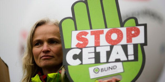 A demonstrator holds a poster against the Comprehensive Economic and Trade Agreement, CETA, during a protest in front of the chancellery in Berlin, Wednesday, Oct. 12, 2016. The Federal Constitutional Court held a hearing Wednesday considering calls from opponents of a European Union-Canada trade deal for an injunction aimed at putting the signing of the accord on ice. (AP Photo/Markus Schreiber)