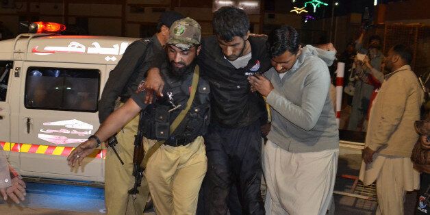A Pakistani volunteer and a police officer rush an injured person to a hospital in Quetta, Pakistan, Monday, Oct. 24, 2016, after two separate attacks in Pakistan. Gunmen stormed a police training center in the restive southwestern province of Baluchistan Monday, leaving several people wounded, hours after another attack near to Quetta leaving two customs officers dead, authorities said. (AP Photo/Arshad Butt)