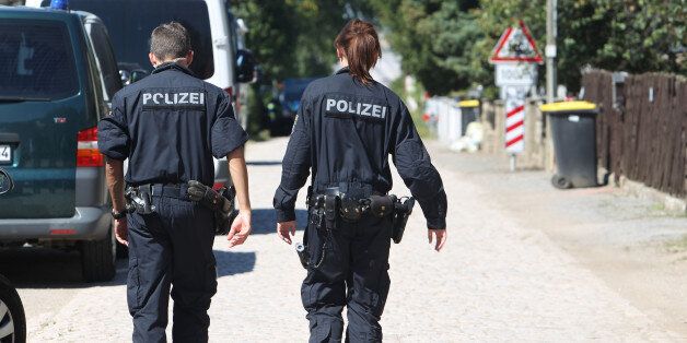 Police officers walk along a road in Reuden, Germany,Thursday Aug. 25, 2016. Three people have been wounded in an armed standoff between police and members of a group that denies the legitimacy of the modern German state in Reuden, eastern Germany. A spokeswoman for police in the eastern state of Saxony-Anhalt says the shootout happened while about 100 police, including a tactical response team, were trying to enforce an eviction order against a 41-year-old âReich citizenâ early Thursday. (Sebastian Willnow/dpa via AP)