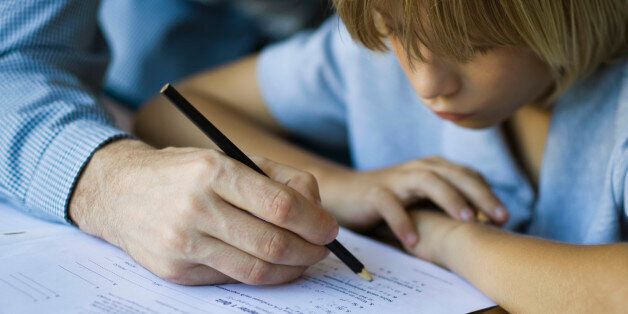 Male junior high student watches as teacher corrects assignment, close-up