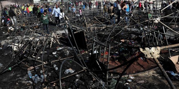 People stand among bed frames burned by a fire which tore through a refugee camp in Diavata, northern Greece, on April 20, 2016, threatening the lives of over 2,300 people who live there.More than a dozen tents were destroyed in the blaze. Police said at least two people were taken to a hospital suffering from smoke inhalation. / AFP / SAKIS MITROLIDIS (Photo credit should read SAKIS MITROLIDIS/AFP/Getty Images)