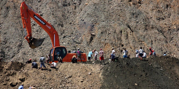 In this Sept. 17, 2015 photo, jade pickers scavenge for scrap jade as earth moving machinery digs in the Hpakant area of Kachin state, northern Myanmar. Villagers in the jungles of Myanmar's northern Kachin state stand upon staggering wealth: Jade worth tens of billions of dollars. Yet they see almost none of that money, even as the precious stone is dug out from under them.(AP Photo/Esther Htsusan)