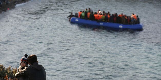 A migrant and a child watches a dinghy of people travel from the Turkish coast to the Greek island of Chios, near Cesme, Turkey, Monday, Nov. 9, 2015. Well over half a million migrants have arrived in Greece from Turkey and the vast majority don't want to stay so head north through the Balkans to other, more prosperous European Union countries. (AP Photo/Emre Tazegul)