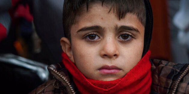 A boy who just arrived on a dinghy with other migrants and refugees from the Turkish coast to the Greek island of Lesbos, looks on, Tuesday, Jan. 26, 2016. More than 850,000 people, most fleeing conflict in Syria and Afghanistan, entered Greece by sea in 2015, according to the UNHCR, and already in 2016, some 35,455 people have arrived despite plunging winter temperatures. (AP Photo/Mstyslav Chernov)