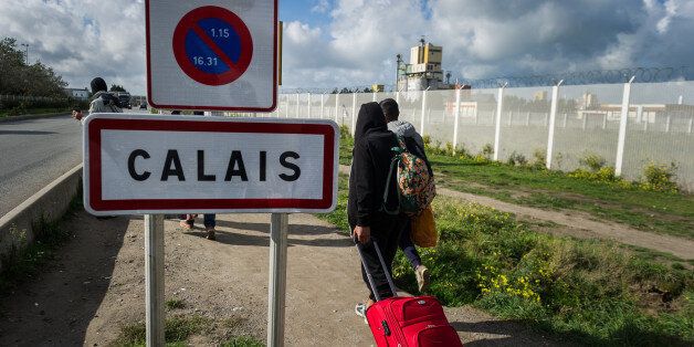 Migrants pass on their way out of the Calais Jungle the town sign of Calais. The refugee camp on the coast to the English Channel is to be cleared in the next few days, according to the French government. In the camp live around the 1000 refugees and wait for the possibility to travel further through the Eurotunnel to the UK. (Photo by Markus Heine/NurPhoto via Getty Images)