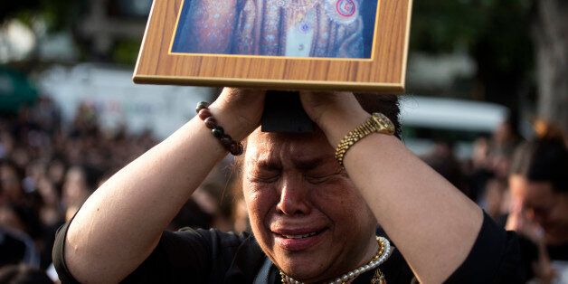 A Thai woman holding up a picture of the late King Bhumibol Adulyadej cries while waiting for a van carrying the body of the king to pay her last respects outside Grand Palace in Bangkok, Friday, Oct. 14, 2016. Bhumibol, the world's longest reigning monarch, died on Thursday at the age of 88. (AP Photo/Wason Wanichakorn)