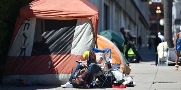A homeless man sleeps in front of his tent along Van Ness Avenue in downtown San Francisco, California on June, 27, 2016. Homelessness is on the rise in the city irking residents and bringing the problem under a spotlight. / AFP / Josh Edelson (Photo credit should read JOSH EDELSON/AFP/Getty Images)